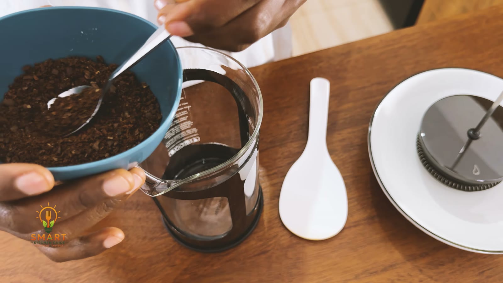 Adding coarse ground coffee to the BAYKA French press carafe with a spoon