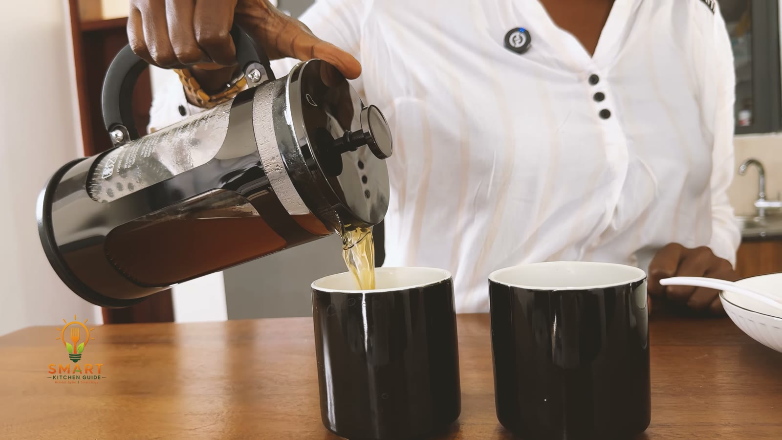 Pouring coffee from the BAYKA French press spout into a black mug
