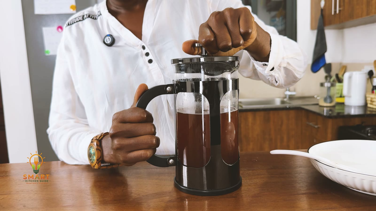 Jackie pressing the plunger of the BAYKA French press down slowly after a four-minute steep