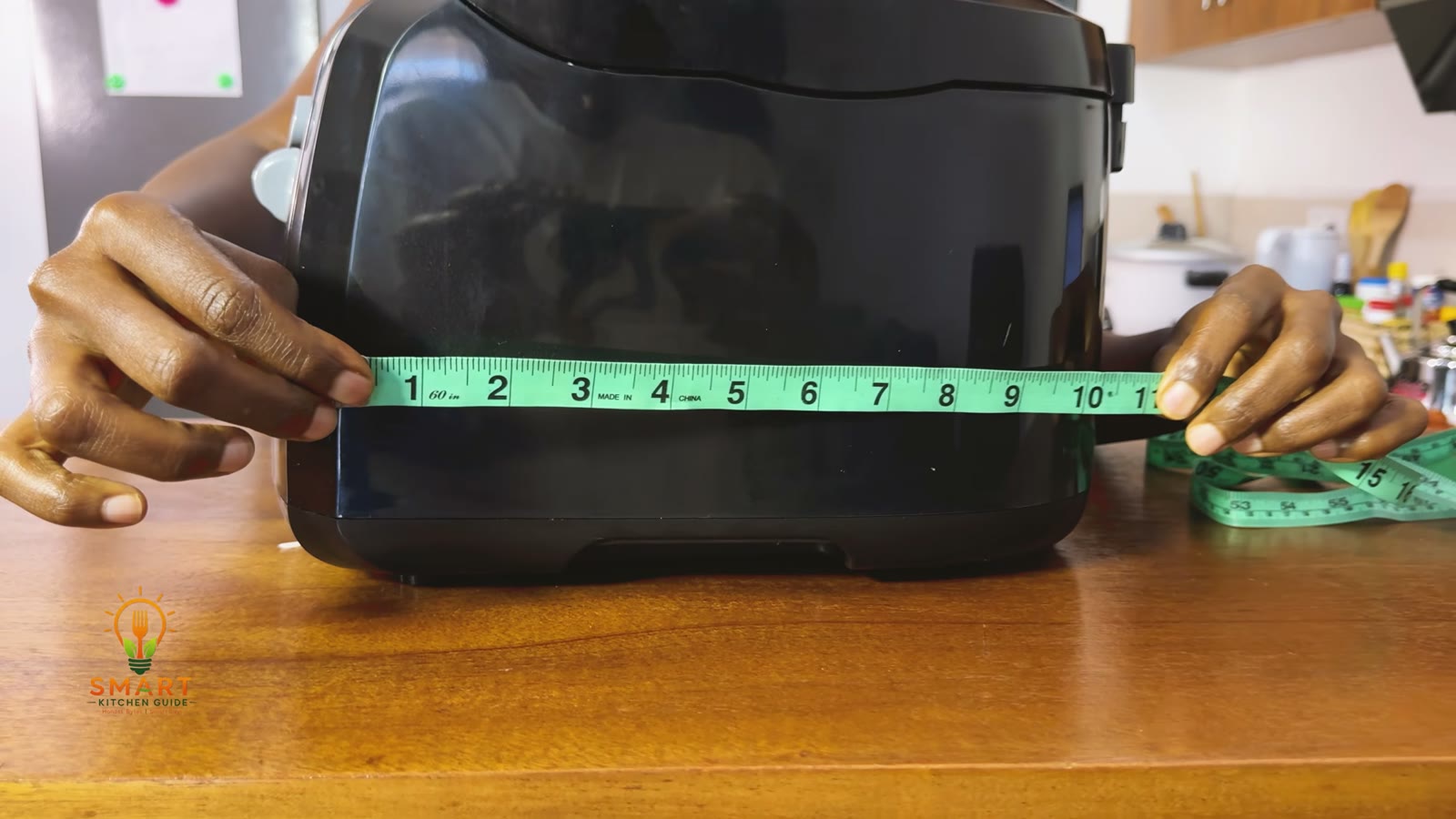 Measuring the width of the Hamilton Beach 35021 deep fryer with a tape measure on the counter