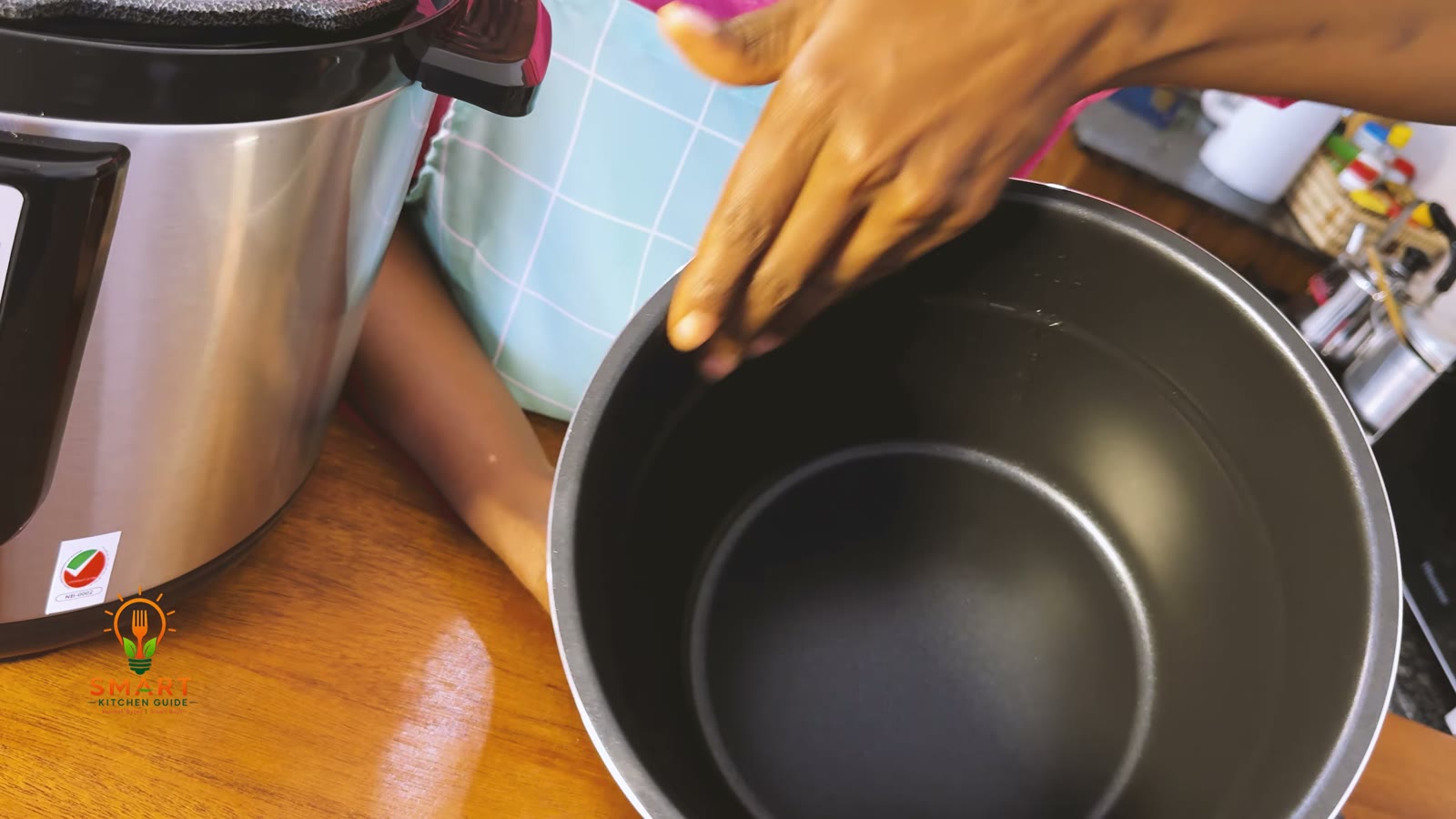 Dark non-stick coated inner pot of the Saachi NL-PC-5306 held next to the cooker body
